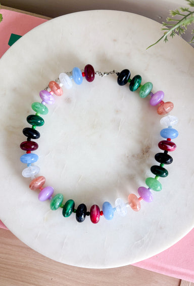 Make a statement with this trendy chunky beaded necklace that's full of color and personality. Featuring bold beads in shades of clear, burgundy, hunter green, green, lilac, blue, and black, this eye-catching accessory is accented with dainty colorful beads between each larger bead for added texture and charm. Whether you're dressing up a simple sweater or adding the finishing touch to your favorite dress, this necklace brings the perfect pop of playful style to any look.