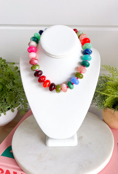 Make a statement with this trendy chunky beaded necklace that's full of color and personality. Featuring bold beads in shades of pink, burgundy, hunter green, green, blue, and black, this eye-catching accessory is accented with dainty colorful pink beads between each larger bead for added texture and charm. Whether you're dressing up a simple sweater or adding the finishing touch to your favorite dress, this necklace brings the perfect pop of playful style to any look.