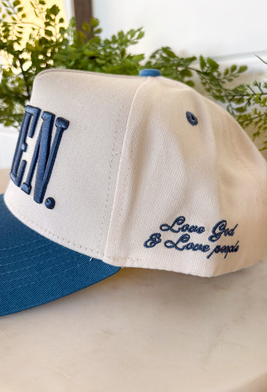 This neutral trucker hat is a meaningful everyday piece with a timeless, faith-forward message. Featuring a dark blue bill with matching embroidered “Amen” on the front, it keeps the look clean and classic. A special touch on the side reads “Love God &amp; Love People,” adding an extra layer of intention and heart. Finished with an adjustable back for a comfortable, just-right fit, this hat is perfect for daily wear, gifting, or sharing a message that matters wherever you go.