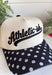 This “Athletic-ish” trucker hat is the perfect mix of cute and a little sarcastic—basically summer energy in one accessory. The neutral base keeps it easy to style, while the black embroidered lettering and polka dot bill add a fun, playful twist. It’s lightweight, breathable, and made for those busy, on-the-go days when you still want to look put together without trying too hard. Whether you're heading to a workout…or just thinking about it, this one gets it.