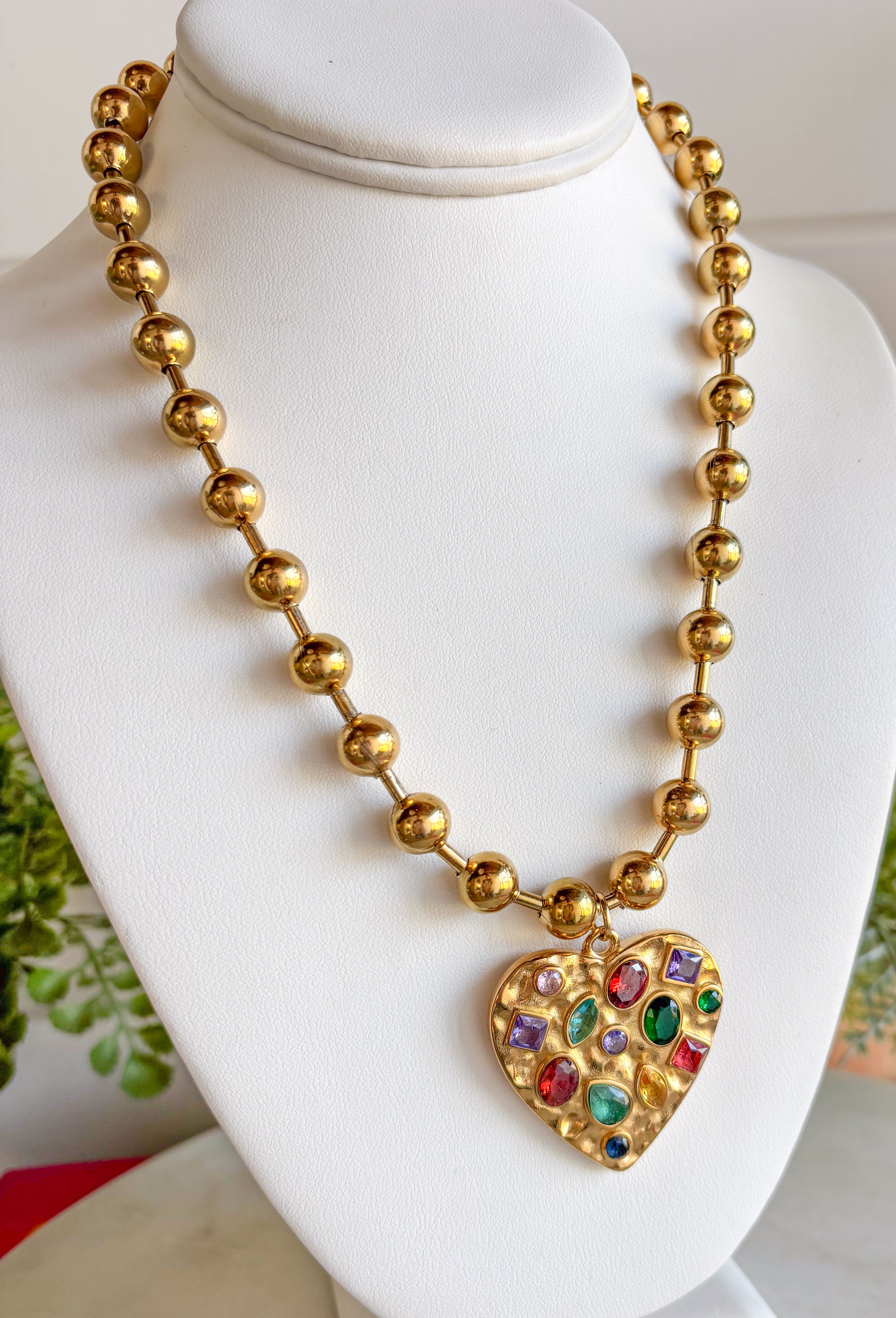 Secure your style with the Confetti Heart Necklace. This unique necklace features a gold heart pendant with jewel toned gems on a fun bubble chain for a unique and trendy look. Layers well with others or wear it on it's own!