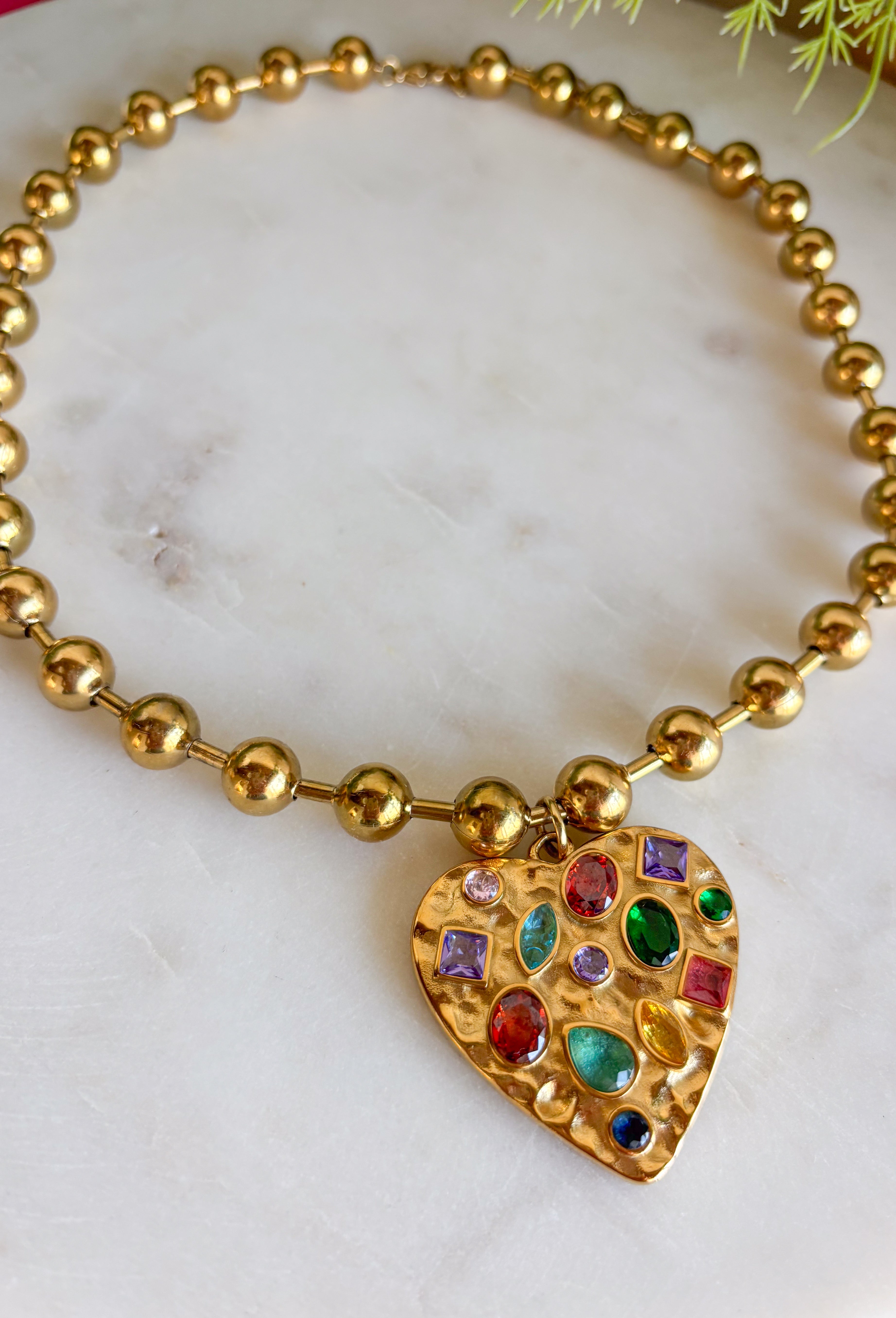 Secure your style with the Confetti Heart Necklace. This unique necklace features a gold heart pendant with jewel toned gems on a fun bubble chain for a unique and trendy look. Layers well with others or wear it on it's own!