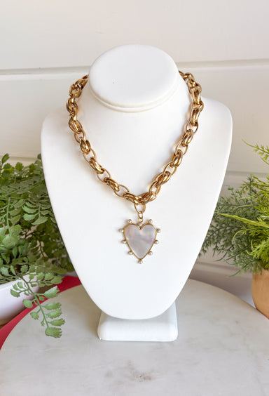 Make a statement with this beautifully crafted chain necklace that blends timeless elegance with modern style. Featuring a bold gold chain, this eye-catching piece is finished with a stunning heart pendant outlined in delicate pearls for the perfect mix of classic charm and sophistication. Whether worn on its own or layered with your favorite necklaces, this versatile accessory instantly elevates everything from cozy sweaters to dresses and blouses, making it a piece you'll treasure season after season.