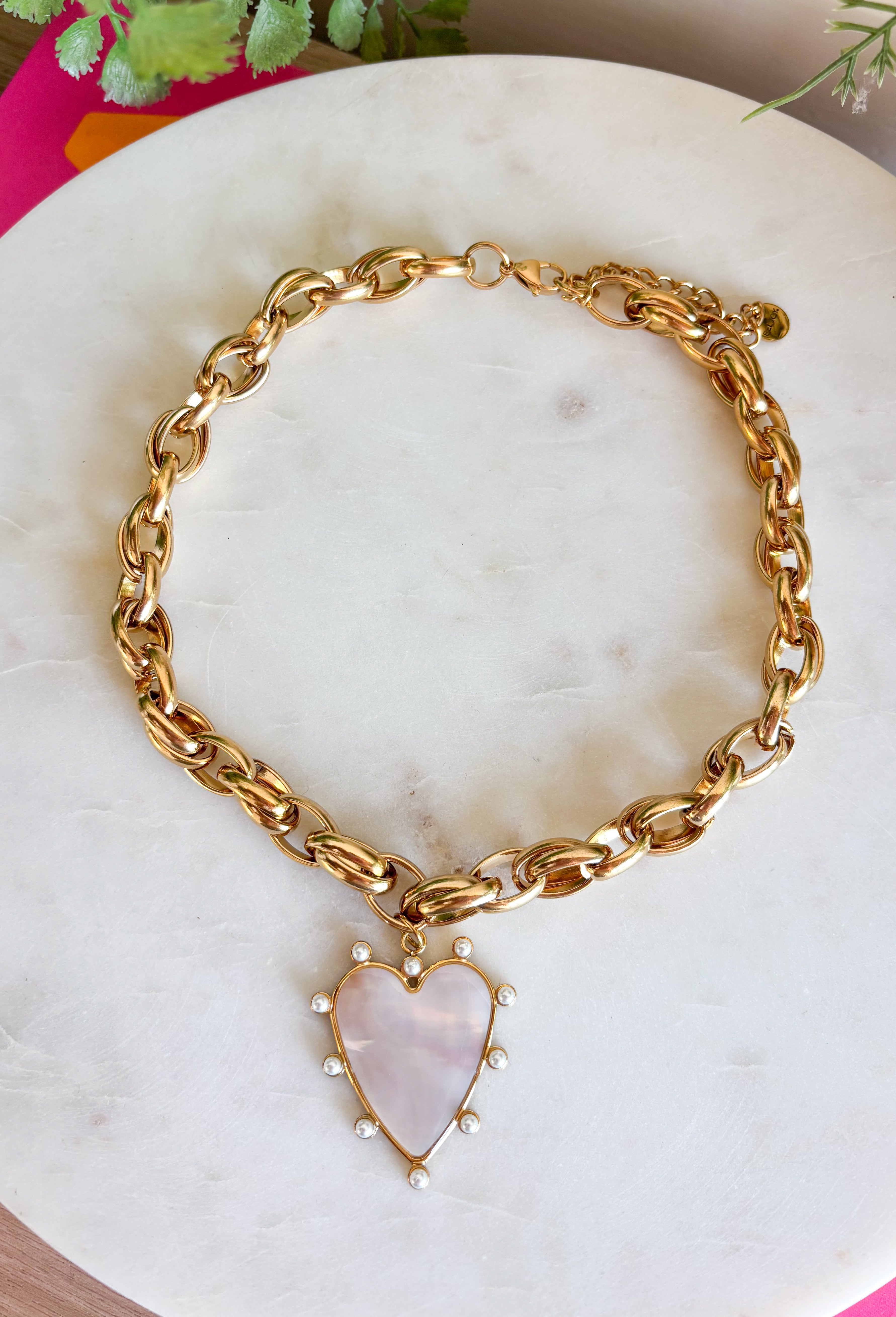 Make a statement with this beautifully crafted chain necklace that blends timeless elegance with modern style. Featuring a bold gold chain, this eye-catching piece is finished with a stunning heart pendant outlined in delicate pearls for the perfect mix of classic charm and sophistication. Whether worn on its own or layered with your favorite necklaces, this versatile accessory instantly elevates everything from cozy sweaters to dresses and blouses, making it a piece you'll treasure season after season.