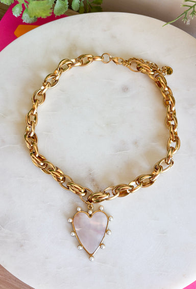 Make a statement with this beautifully crafted chain necklace that blends timeless elegance with modern style. Featuring a bold gold chain, this eye-catching piece is finished with a stunning heart pendant outlined in delicate pearls for the perfect mix of classic charm and sophistication. Whether worn on its own or layered with your favorite necklaces, this versatile accessory instantly elevates everything from cozy sweaters to dresses and blouses, making it a piece you'll treasure season after season.