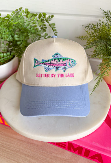 This trucker hat is made for long lake days, sunshine, and making memories by the water! Featuring a colorful embroidered fish and "Better By The Lake" stitched in bright pink, it brings all the fun summer vibes. The neutral crown keeps it easy to style, while the periwinkle bill adds the perfect pop of color. Whether you're spending the day on the boat, relaxing at the cabin, or heading out for a weekend getaway, this hat is the perfect finishing touch. 