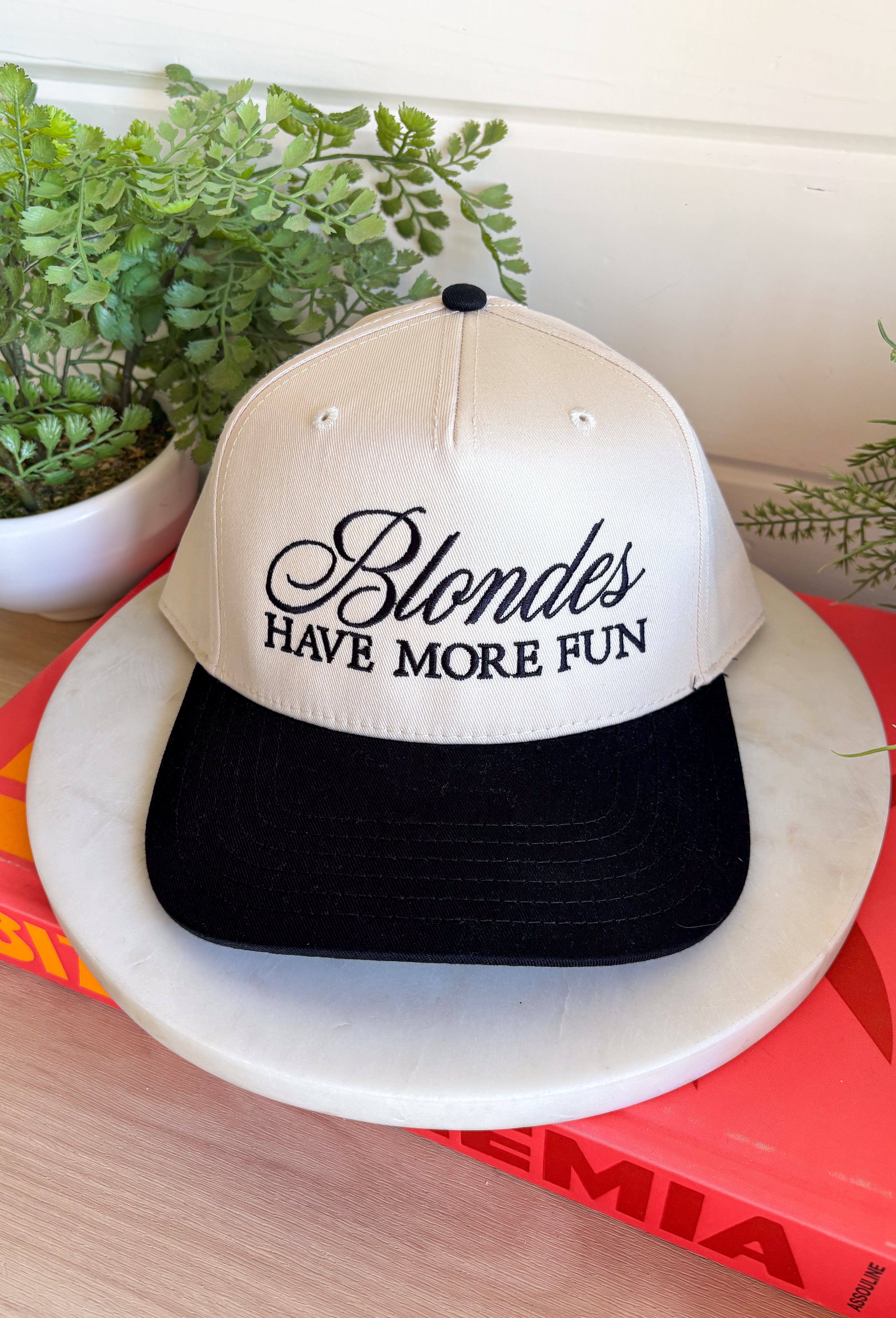 This trucker hat is bringing the attitude—in the best way! Featuring “Blondes Have More Fun” embroidered across the front, it’s the perfect mix of playful and a little bold. The tan base with a black bill keeps it easy to style, while the statement graphic does all the talking. Whether you're heading out for errands, a casual day with friends, or just embracing your blonde era, this hat adds that fun finishing touch. 