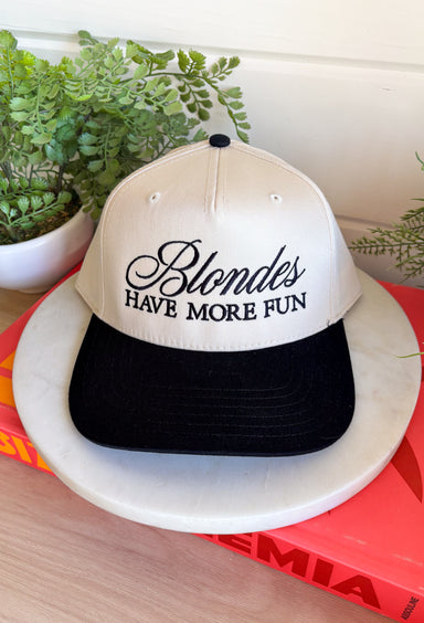 This trucker hat is bringing the attitude—in the best way! Featuring “Blondes Have More Fun” embroidered across the front, it’s the perfect mix of playful and a little bold. The tan base with a black bill keeps it easy to style, while the statement graphic does all the talking. Whether you're heading out for errands, a casual day with friends, or just embracing your blonde era, this hat adds that fun finishing touch. 