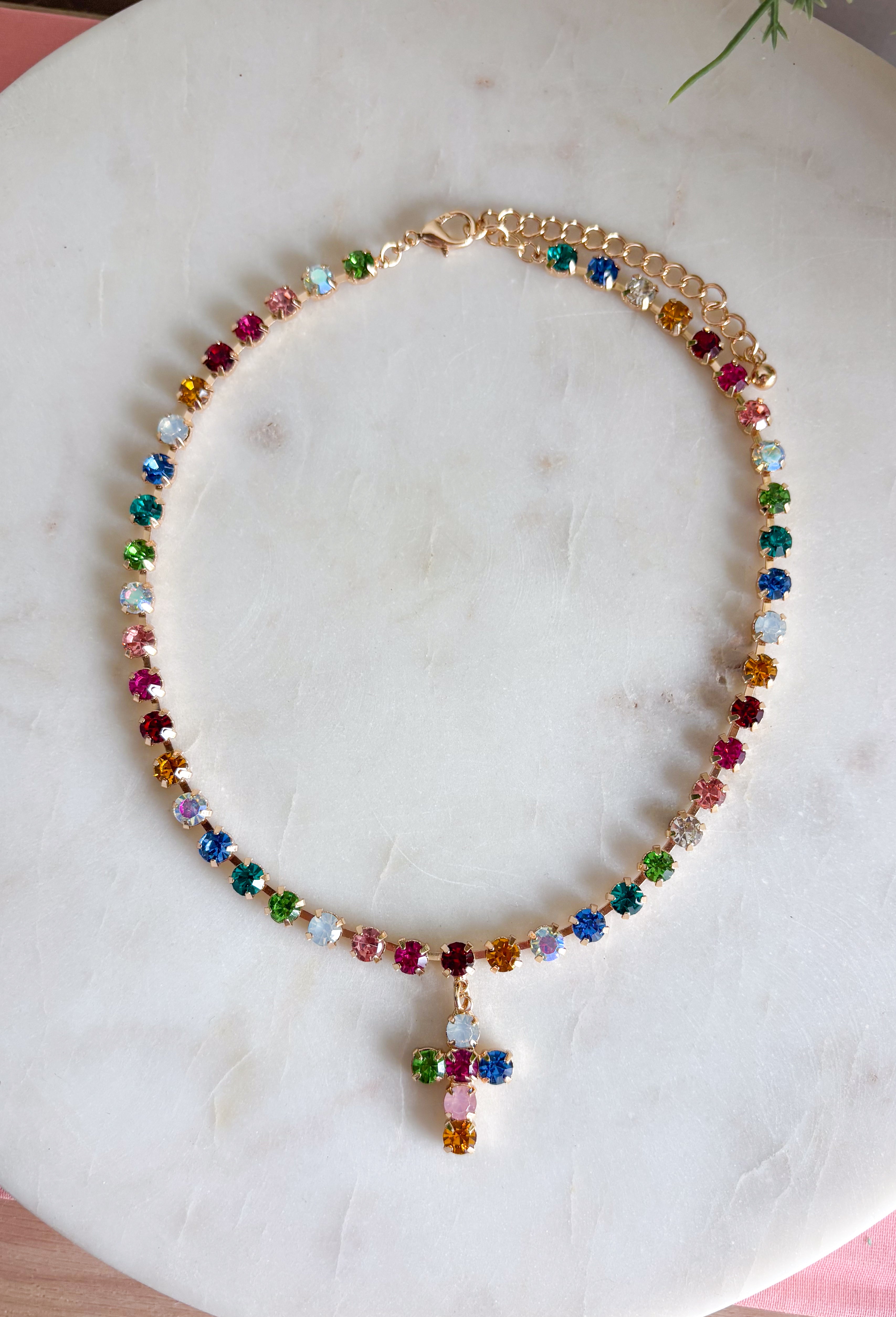Add a meaningful touch of color to your jewelry collection with this beautiful cross necklace. Featuring a strand of colorful rhinestone crystals in shades of red, blue, green, pink, and gold, this eye-catching piece is finished with a matching cross pendant for the perfect blend of faith and style. The vibrant colors and delicate gold accents make it a standout accessory that's easy to wear for both everyday outfits and special occasions.