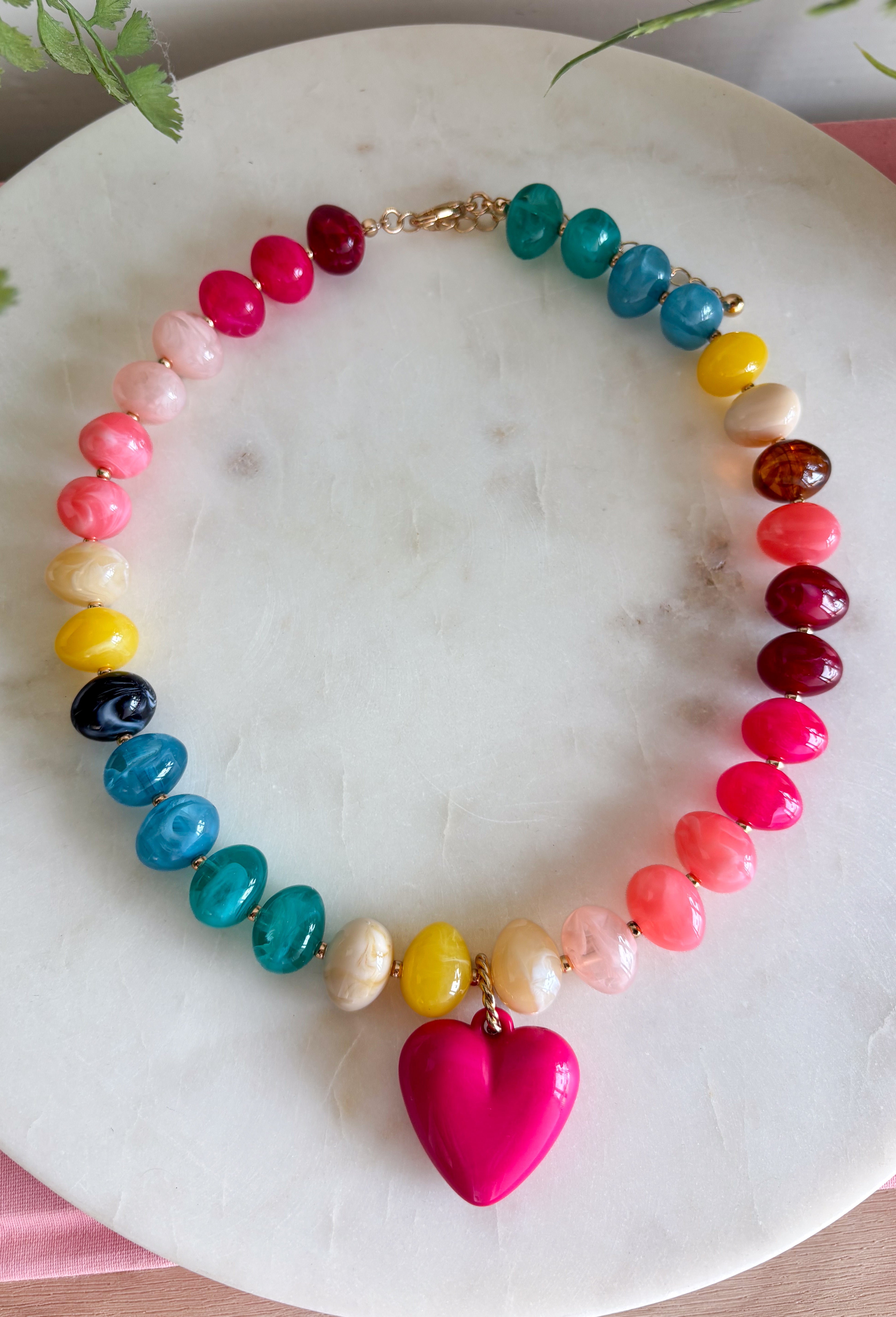 A little color and a lot of heart make this beaded necklace such a fun addition to your jewelry collection. Colorful beads in blue, yellow, burgundy, and pink create a playful mix, while the pink heart charm pendant adds an extra-sweet focal point. Finished with 18K gold-dipped details, it has just the right touch of shine to bring the whole look together. Wear it solo for a cheerful pop of color or layer it with your favorite gold necklaces for a fun, collected look.