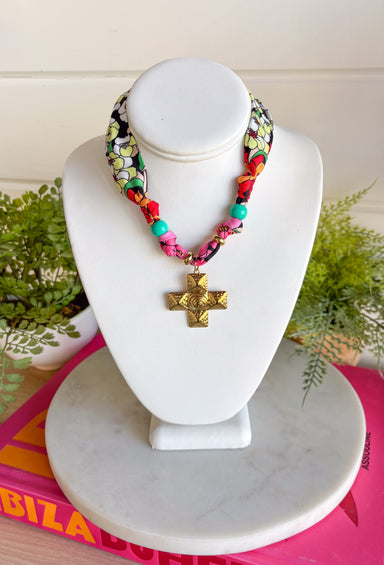 A little bold, a little western, and full of personality! This colorful bandana scarf necklace blends vibrant prints with meaningful details for a statement accessory you’ll love wearing. The scarf features black and white florals paired with bright stripes in pink, green, red, orange, and yellow for a fun pop of color. Finished with a gold textured cross pendant and a turquoise bead accent, this piece brings together playful style with a hint of western charm. 