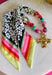 A little bold, a little western, and full of personality! This colorful bandana scarf necklace blends vibrant prints with meaningful details for a statement accessory you’ll love wearing. The scarf features black and white florals paired with bright stripes in pink, green, red, orange, and yellow for a fun pop of color. Finished with a gold textured cross pendant and a turquoise bead accent, this piece brings together playful style with a hint of western charm. 