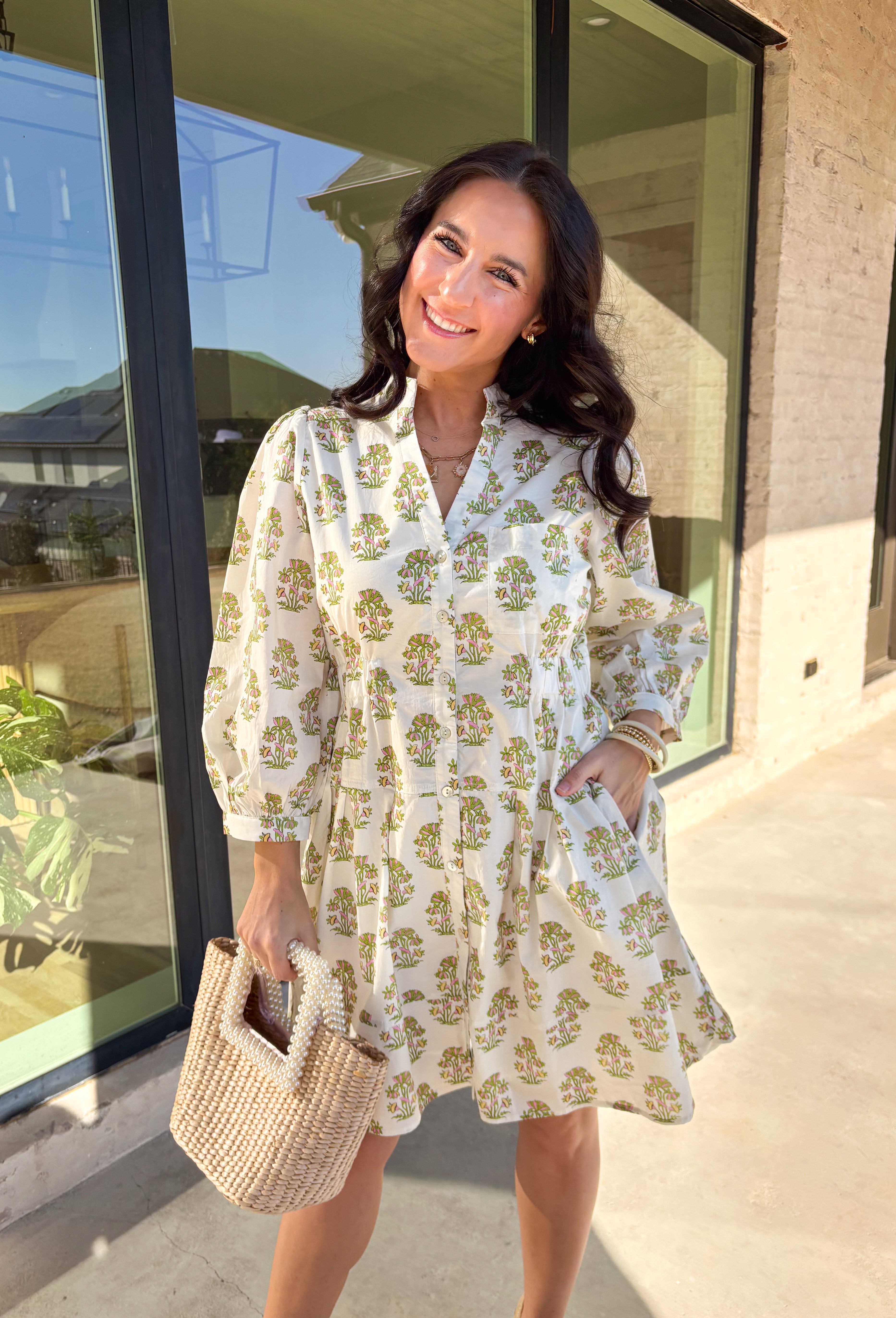 Fresh, feminine, and effortlessly flattering, this off-white long sleeve dress is made for spring days ahead. Featuring a green and pink floral print throughout, it feels light, cheerful, and easy to wear. The button-down front and front pocket add a classic touch, while smocking at the waist creates a comfortable, flattering fit that still feels relaxed. Fully lined and crafted from breathable cotton, this dress is perfect for brunch, showers, or any day you want to feel put together without trying too har