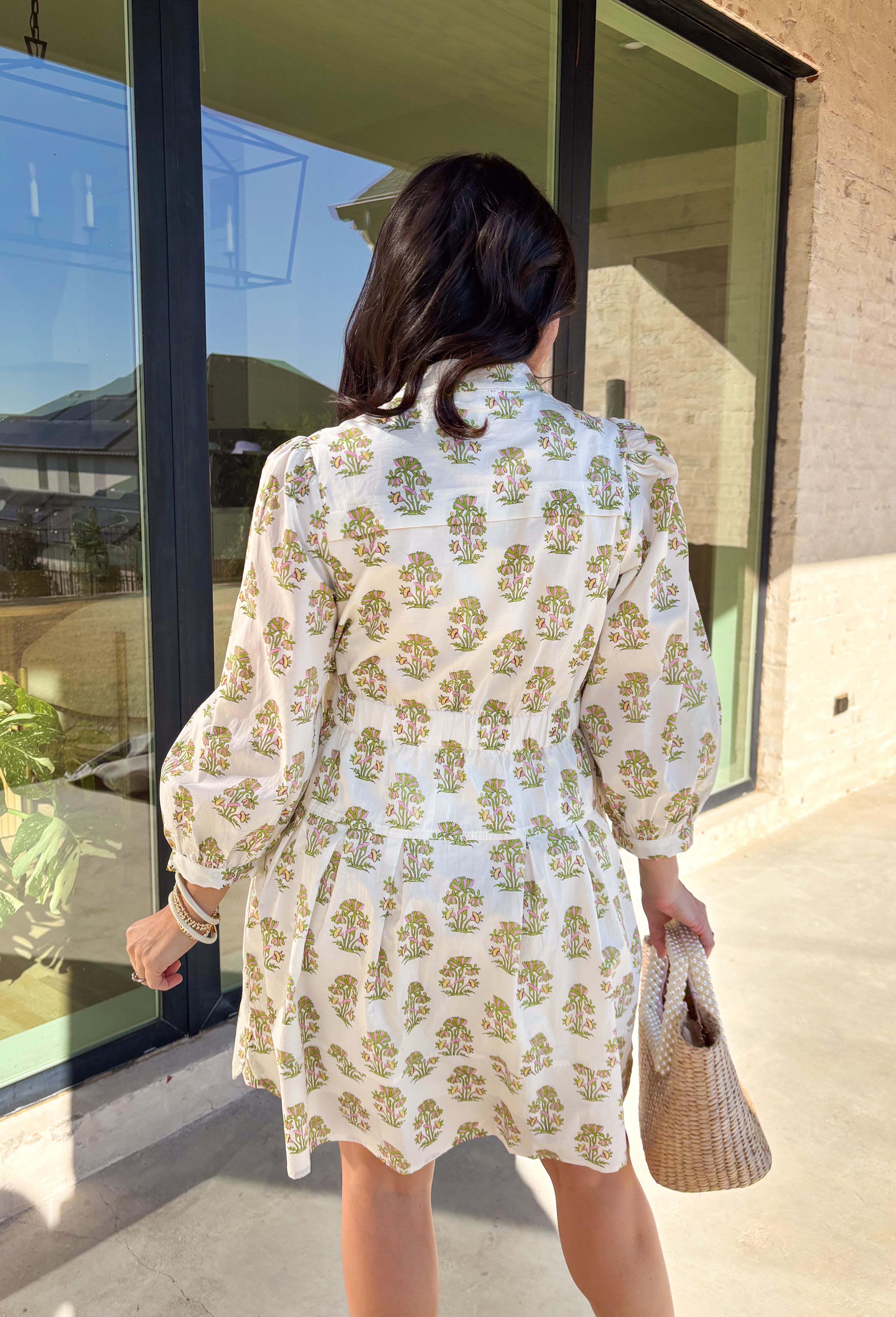 Fresh, feminine, and effortlessly flattering, this off-white long sleeve dress is made for spring days ahead. Featuring a green and pink floral print throughout, it feels light, cheerful, and easy to wear. The button-down front and front pocket add a classic touch, while smocking at the waist creates a comfortable, flattering fit that still feels relaxed. Fully lined and crafted from breathable cotton, this dress is perfect for brunch, showers, or any day you want to feel put together without trying too har