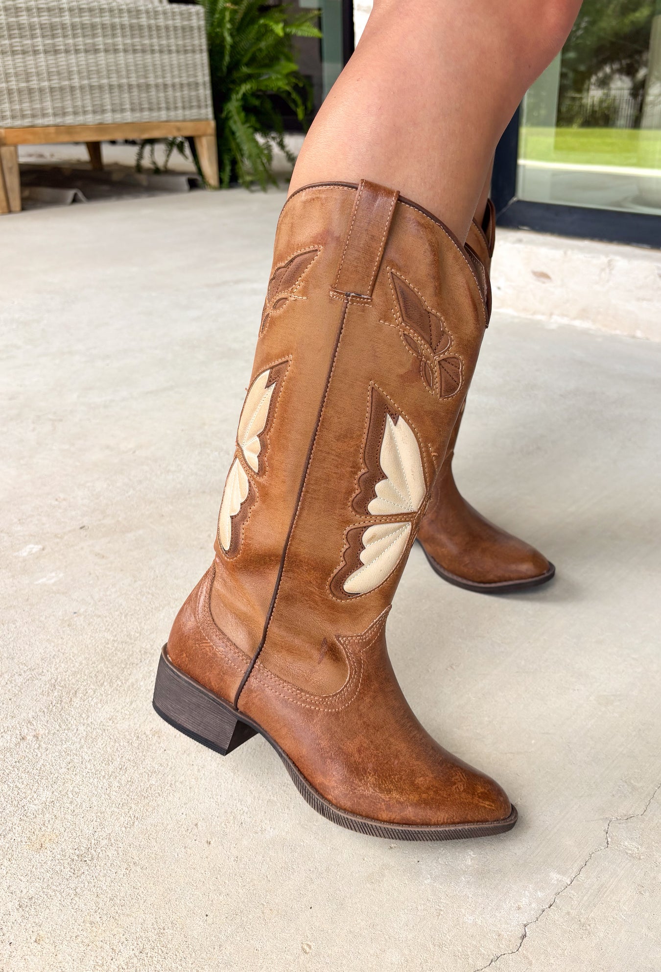 A little western, a little whimsical! These tan cowgirl boots by Coconuts by Matisse feature beautiful butterfly detailing across the front for a fun, feminine twist on a classic silhouette. The tan color keeps them easy to style, while the butterflies add that extra something special. Designed with an almond toe and stacked heel, these boots offer a flattering shape with comfortable wear. Pull-on loops make them easy to slip on and go—perfect for pairing with dresses, denim, or anything in between.