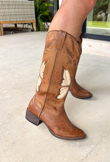 A little western, a little whimsical! These tan cowgirl boots by Coconuts by Matisse feature beautiful butterfly detailing across the front for a fun, feminine twist on a classic silhouette. The tan color keeps them easy to style, while the butterflies add that extra something special. Designed with an almond toe and stacked heel, these boots offer a flattering shape with comfortable wear. Pull-on loops make them easy to slip on and go—perfect for pairing with dresses, denim, or anything in between.