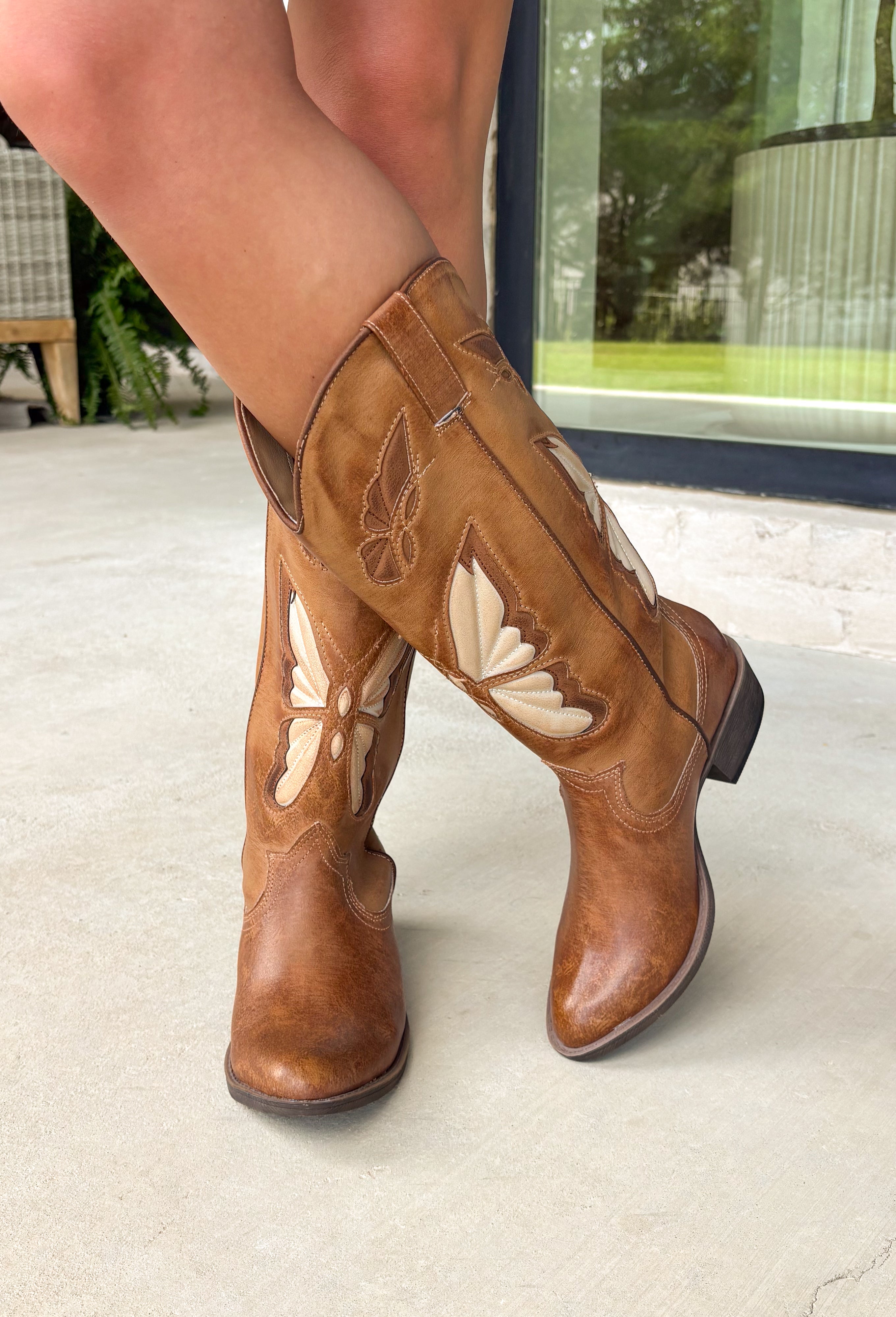A little western, a little whimsical! These tan cowgirl boots by Coconuts by Matisse feature beautiful butterfly detailing across the front for a fun, feminine twist on a classic silhouette. The tan color keeps them easy to style, while the butterflies add that extra something special. Designed with an almond toe and stacked heel, these boots offer a flattering shape with comfortable wear. Pull-on loops make them easy to slip on and go—perfect for pairing with dresses, denim, or anything in between.