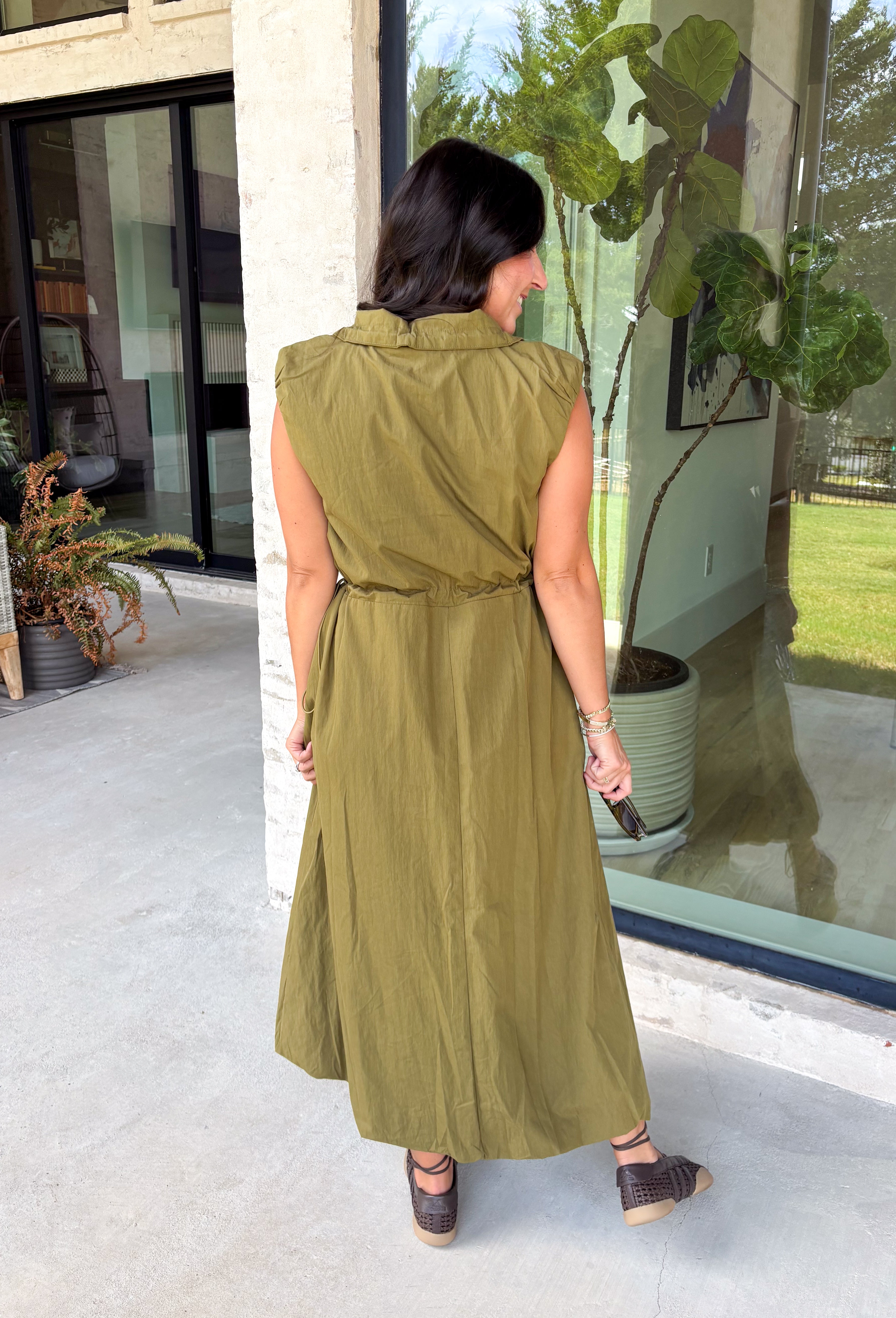 Meet your new throw-on-and-go favorite with this olive utility-inspired midi dress from Entro. The classic olive color keeps it versatile, while the zipper-front closure and adjustable waist give it a sporty, modern feel. A bubble hem adds shape and a fun unexpected finish, while the sleeveless silhouette makes it easy to wear now and layer as the temperatures cool down. Complete with convenient side pockets, this dress is ready for busy workdays, weekend plans, travel days, and everything in between.