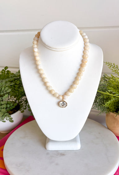 Elegant, timeless, and effortlessly versatile, this ivory beaded necklace is the perfect accessory to elevate any outfit. Featuring beautiful ivory beads, this classic piece is accented with a dazzling crystal rhinestone charm that adds just the right amount of shimmer. Whether you're dressing up a cozy sweater, styling your favorite blouse, or adding a polished finishing touch to a special occasion look, this necklace is one you'll reach for season after season.