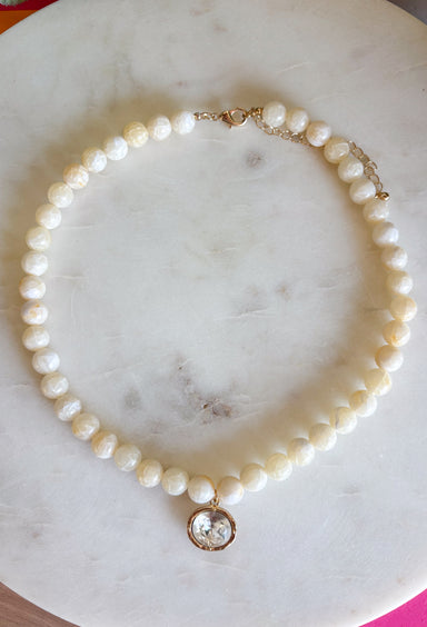Elegant, timeless, and effortlessly versatile, this ivory beaded necklace is the perfect accessory to elevate any outfit. Featuring beautiful ivory beads, this classic piece is accented with a dazzling crystal rhinestone charm that adds just the right amount of shimmer. Whether you're dressing up a cozy sweater, styling your favorite blouse, or adding a polished finishing touch to a special occasion look, this necklace is one you'll reach for season after season.