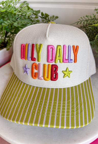 Slow down and enjoy the little moments with this colorful trucker hat. Featuring "Dilly Dally Club" embroidered in vibrant colors alongside a playful purple and lime green star, this hat is full of personality and happy vibes. The lime green bill with neutral stripe detailing and coordinating top button make it a standout accessory that's perfect for everything from weekend adventures to coffee runs and casual days out.