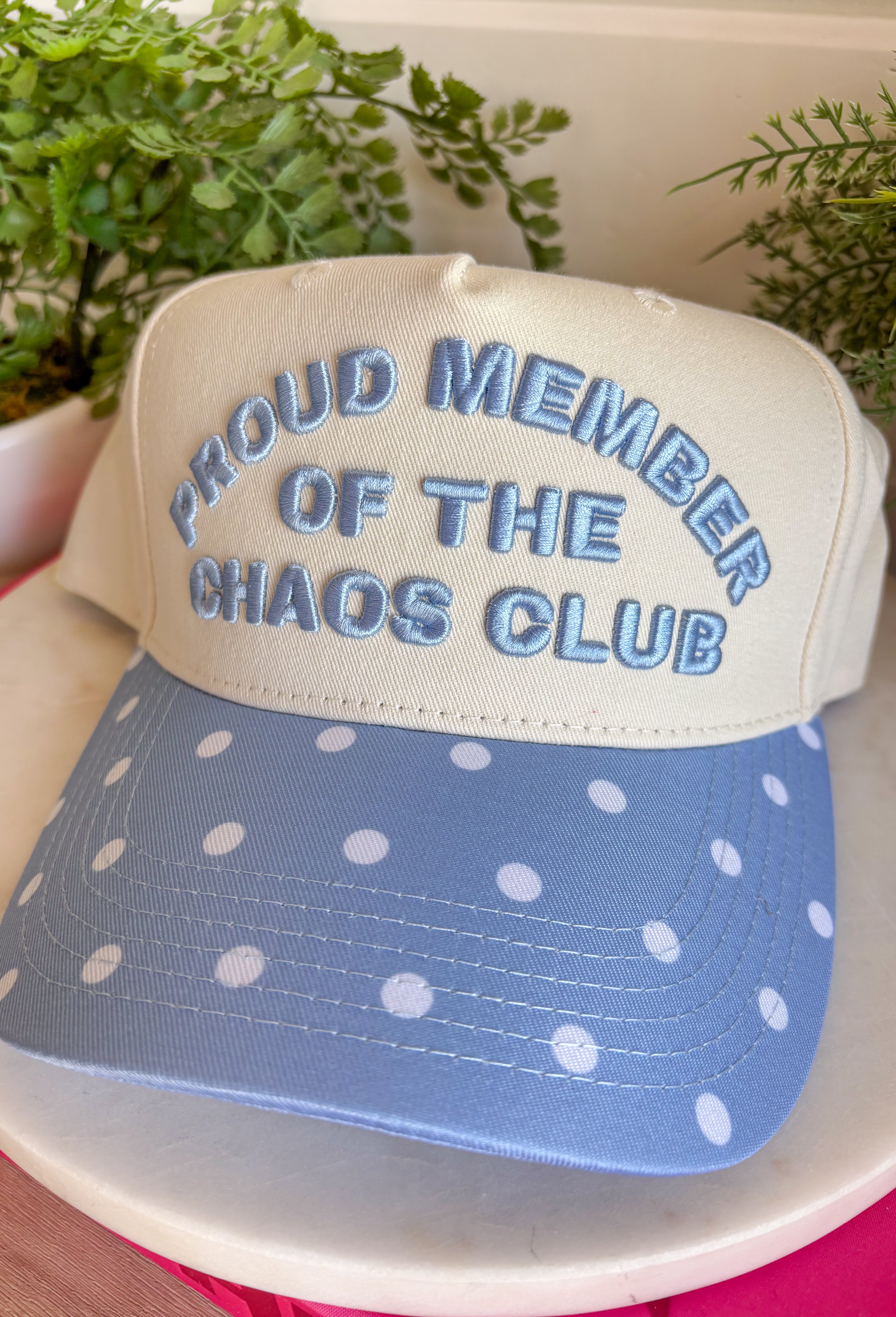 Wear your badge of honor with a smile in this playful trucker hat. Featuring "Proud Member Of The Chaos Club" embroidered in a classic denim blue, this hat is made for busy days, endless to-do lists, and embracing every bit of the fun along the way. The denim blue bill with an off white polka dot print adds a charming vintage-inspired touch, making it the perfect accessory for school drop-offs, errands, weekend adventures, and everything in between.