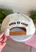 A little reminder to appreciate the good stuff! This neutral trucker hat from Etta &amp; East features colorful embroidered “How Lucky Are We” lettering across the front for a playful pop against the classic neutral design. A rich brown bill gives it an autumn-ready feel, while an embroidered horseshoe on the side adds an extra lucky touch. Finished with an adjustable fit, it’s an easy grab-and-go accessory for football weekends, coffee runs, road trips, and everyday errands.