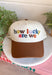 A little reminder to appreciate the good stuff! This neutral trucker hat from Etta &amp; East features colorful embroidered “How Lucky Are We” lettering across the front for a playful pop against the classic neutral design. A rich brown bill gives it an autumn-ready feel, while an embroidered horseshoe on the side adds an extra lucky touch. Finished with an adjustable fit, it’s an easy grab-and-go accessory for football weekends, coffee runs, road trips, and everyday errands.