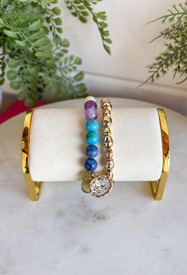 The easiest way to add a fun pop of color to your everyday look! This set of two pull-on bracelets is designed for effortless styling, featuring one colorful beaded bracelet with a sparkling crystal charm embellishment and one classic gold beaded bracelet. Wear them together for a perfectly layered look, or style each one on its own to complement any outfit. 