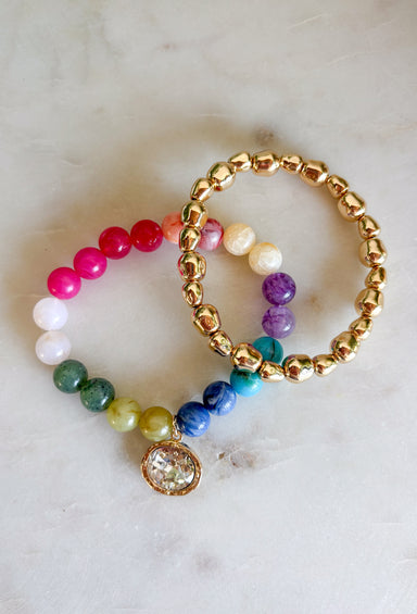 The easiest way to add a fun pop of color to your everyday look! This set of two pull-on bracelets is designed for effortless styling, featuring one colorful beaded bracelet with a sparkling crystal charm embellishment and one classic gold beaded bracelet. Wear them together for a perfectly layered look, or style each one on its own to complement any outfit. 
