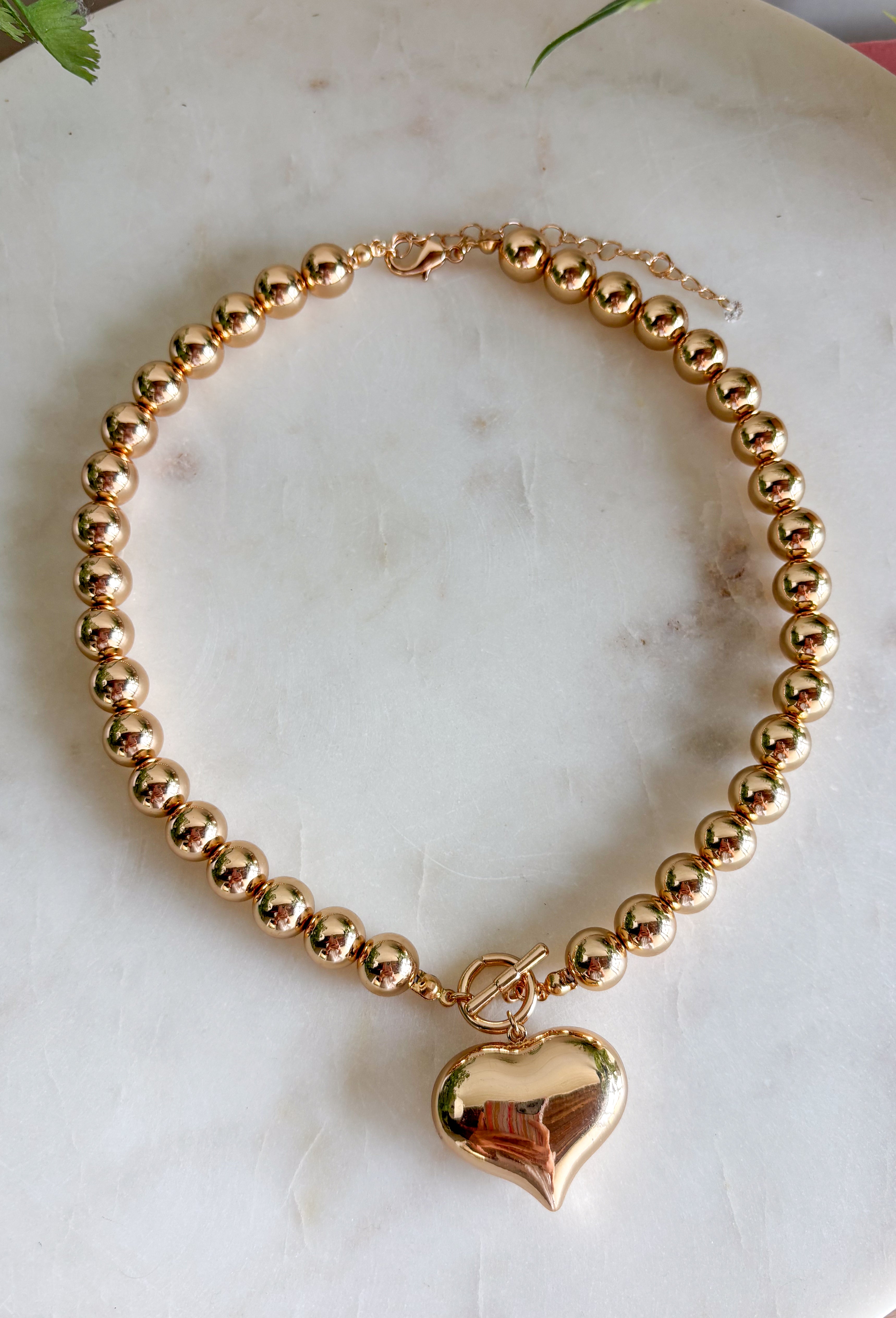A classic gold necklace gets a sweet statement-making touch with this heart pendant design from Garden Party. Gold beading gives the necklace plenty of texture and shine, while the gold heart pendant creates a timeless focal point at the center. A toggle detail adds another eye-catching element and gives the piece a little extra personality. Easy to dress up or down, it’s the kind of necklace that works just as well with your everyday favorites as it does with dresses and special occasion looks.