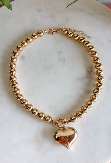 A classic gold necklace gets a sweet statement-making touch with this heart pendant design from Garden Party. Gold beading gives the necklace plenty of texture and shine, while the gold heart pendant creates a timeless focal point at the center. A toggle detail adds another eye-catching element and gives the piece a little extra personality. Easy to dress up or down, it’s the kind of necklace that works just as well with your everyday favorites as it does with dresses and special occasion looks.