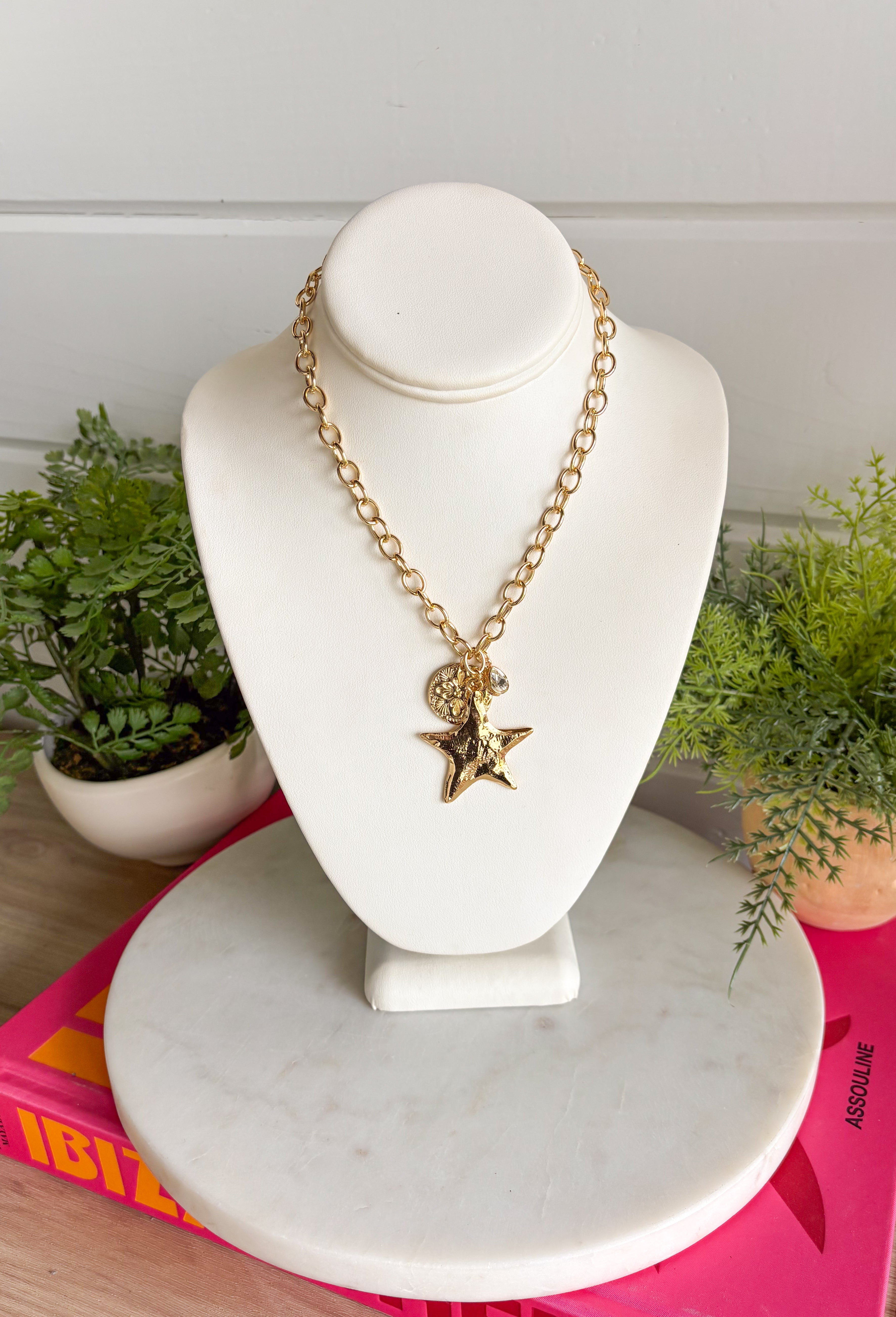 A little sparkle with a playful star detail! This gold open chain necklace features a textured star pendant paired with a textured circle charm and a delicate crystal accent for the perfect hint of shine. The layered charm design adds dimension and personality while still feeling effortless and easy to wear. Trendy yet timeless, this piece looks beautiful worn on its own or layered with your favorite gold necklaces. 