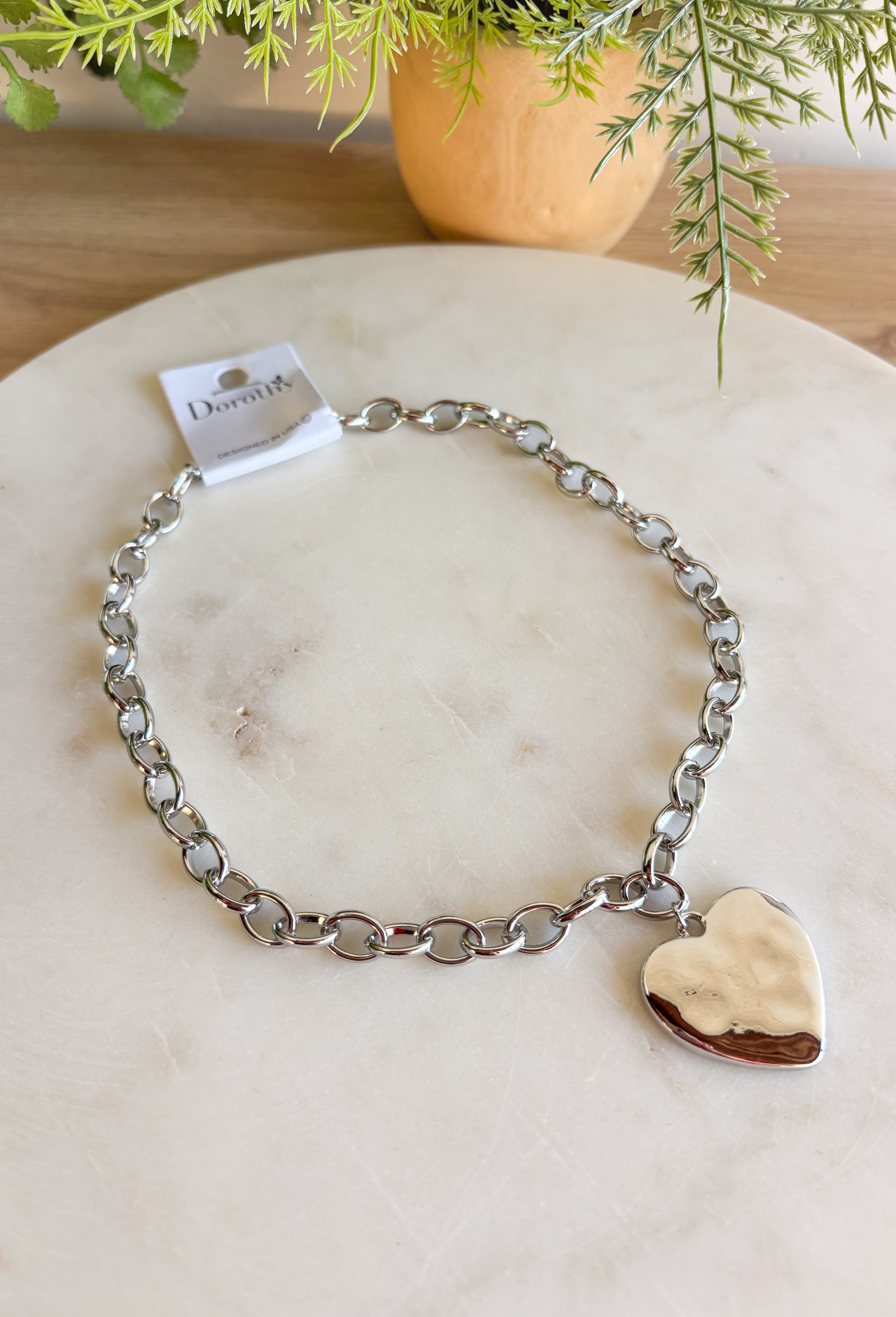 Simple, stylish, and oh-so versatile—this silver chain necklace is the perfect finishing touch for any look. Designed with a textured heart charm, it adds just the right amount of detail and personality without overpowering your outfit. With its adjustable extender, you can wear it closer to the neckline for layering or a little longer on its own. A timeless piece you’ll keep reaching for, no matter the occasion.