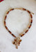 Rich earthy tones and meaningful details come together beautifully in this charm necklace that's perfect for the fall season. Featuring warm brown beads, this eye-catching piece is adorned with a mix of charms, including a gold cross, a natural brown stone, a sparkling brown crystal, and hammered gold accents for added texture and shine. Whether worn with a cozy sweater or your favorite dress, this unique necklace adds effortless charm and personality to every outfit.