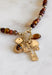 Rich earthy tones and meaningful details come together beautifully in this charm necklace that's perfect for the fall season. Featuring warm brown beads, this eye-catching piece is adorned with a mix of charms, including a gold cross, a natural brown stone, a sparkling brown crystal, and hammered gold accents for added texture and shine. Whether worn with a cozy sweater or your favorite dress, this unique necklace adds effortless charm and personality to every outfit.