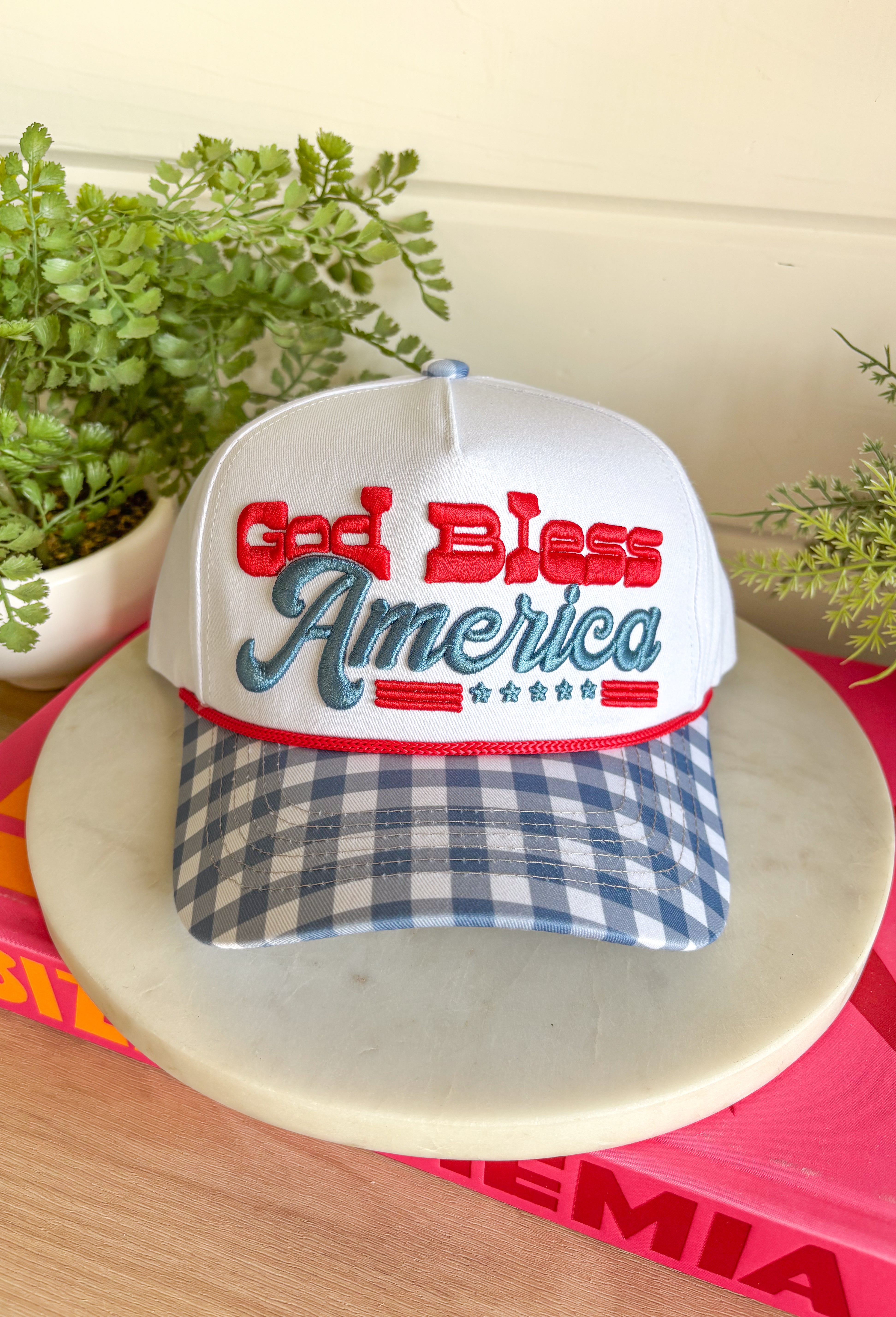 This white trucker hat with a blue gingham bill is the sweetest patriotic touch for your summer lineup! The embroidered “God Bless America” in red and blue adds a festive pop, while the gingham detail keeps it feeling fresh and fun. Perfect for the 4th of July, lake days, or backyard BBQs, this hat is both cute and practical with its breathable design and adjustable fit. It’s an easy way to pull your whole look together while staying cool in the sun. 