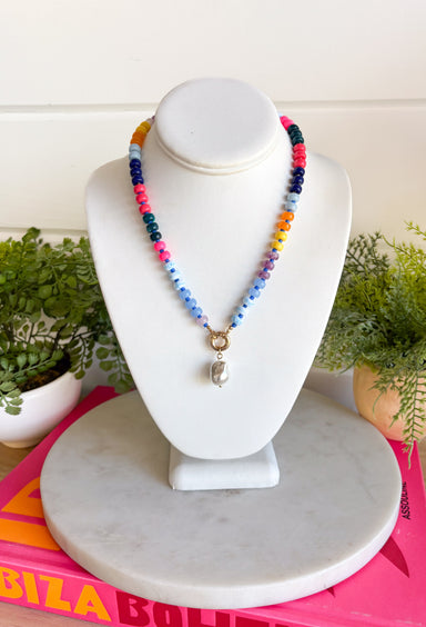 This colorful beaded necklace is the perfect accessory for adding a playful pop to your summer style! Featuring vibrant beads, a chic gold toggle clasp, and a pearl pendant charm, it combines trendy details with a timeless touch. The mix of color and pearl accents creates a fun, elevated look that's easy to wear with everything from casual tanks to breezy dresses. Whether you're heading on vacation, brunch with friends, or simply brightening up an everyday outfit, this necklace is sure to become a favorite.