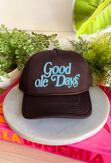 A little nostalgic and a whole lot cute! This brown trucker hat features “Good Ole Days” in a soft light blue, giving it that easy, throwback charm. The neutral brown paired with the pop of blue makes it effortless to style while still adding personality to your everyday look.&nbsp;With a classic mesh backing for breathability and an adjustable fit, this one is perfect for concerts, road trips, or just soaking up slow, sweet moments. It’s the kind of hat that feels timeless from the very first wear.