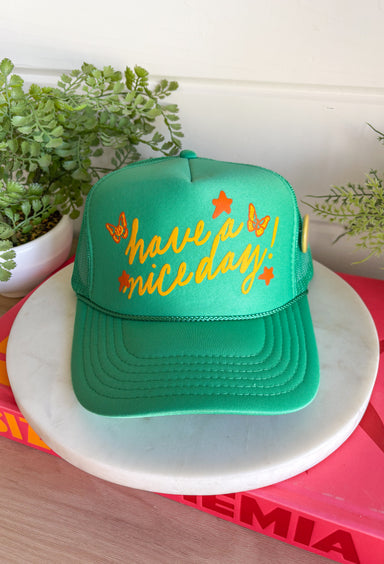 All the good vibes in one hat! This green trucker hat features “Have A Nice Day!” in a warm mustard tone, surrounded by playful orange and mustard butterflies and star details for the happiest little pop of personality. A small yellow button on the side that reads “Sorry Out of Office” adds a fun, laid-back touch that makes this hat even more unique. With a breathable mesh backing and adjustable fit, it’s perfect for sunny days, weekend plans, or anytime you're in your carefree era.