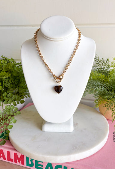 Warm tortoise and classic gold come together in this heart necklace from Garden Party. The gold chain features interlocking gold details leading to a brown tortoise heart pendant, creating a fun mix of shapes, texture, and rich neutral color. The tortoise pattern gives each outfit a little extra personality while still being easy to pair with all your favorite fall and winter shades. Wear it with cozy sweaters, simple blouses, or dresses whenever you want a statement piece that still feels effortless.