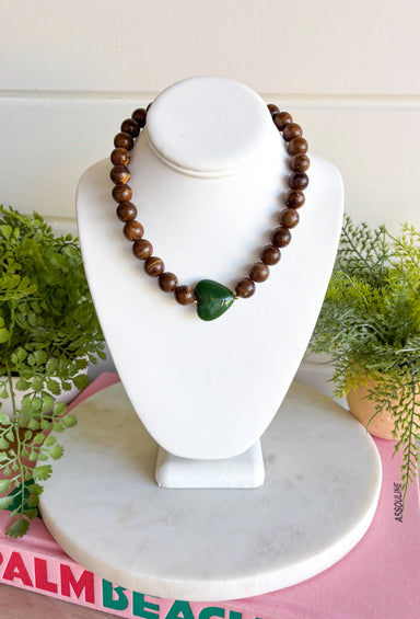 Warm, earthy color gives this beaded necklace a fun seasonal feel. Brown beads create a neutral base, while the hunter green sideways heart adds an unexpected pop of color at the front. The rich combination of brown and green makes it especially easy to pair with cozy knits, denim, and all the deeper shades of fall and winter. Wear it on its own for a simple statement or mix it into your favorite layered necklace stack.
