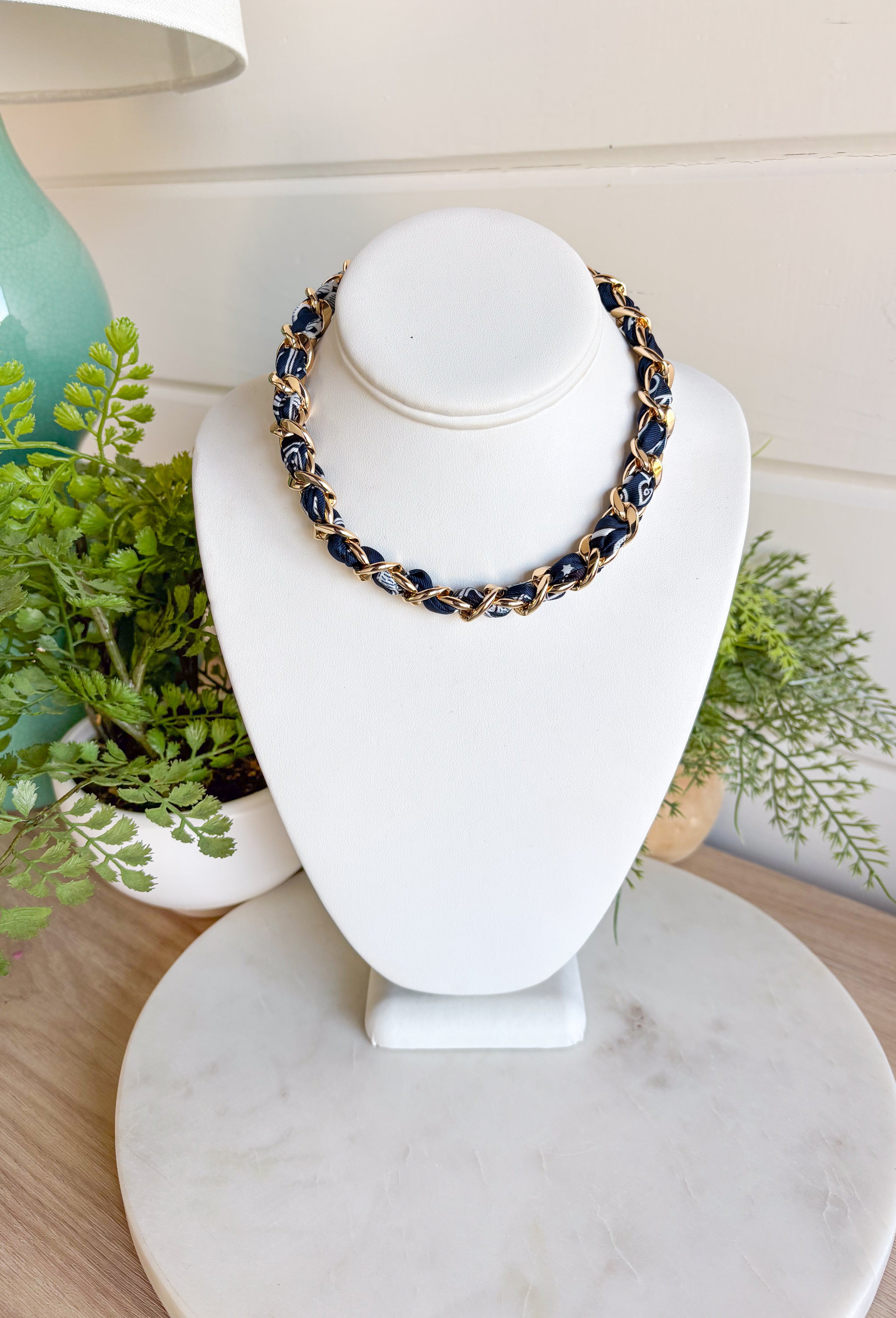 Add a bold yet timeless touch to your look with this navy bandana and gold chain necklace. The chunky gold chain is threaded with a navy bandana, creating the perfect mix of edgy and chic. Whether you’re dressing up for a night out or keeping it casual with a tee and jeans, this statement piece brings effortless style to every season.