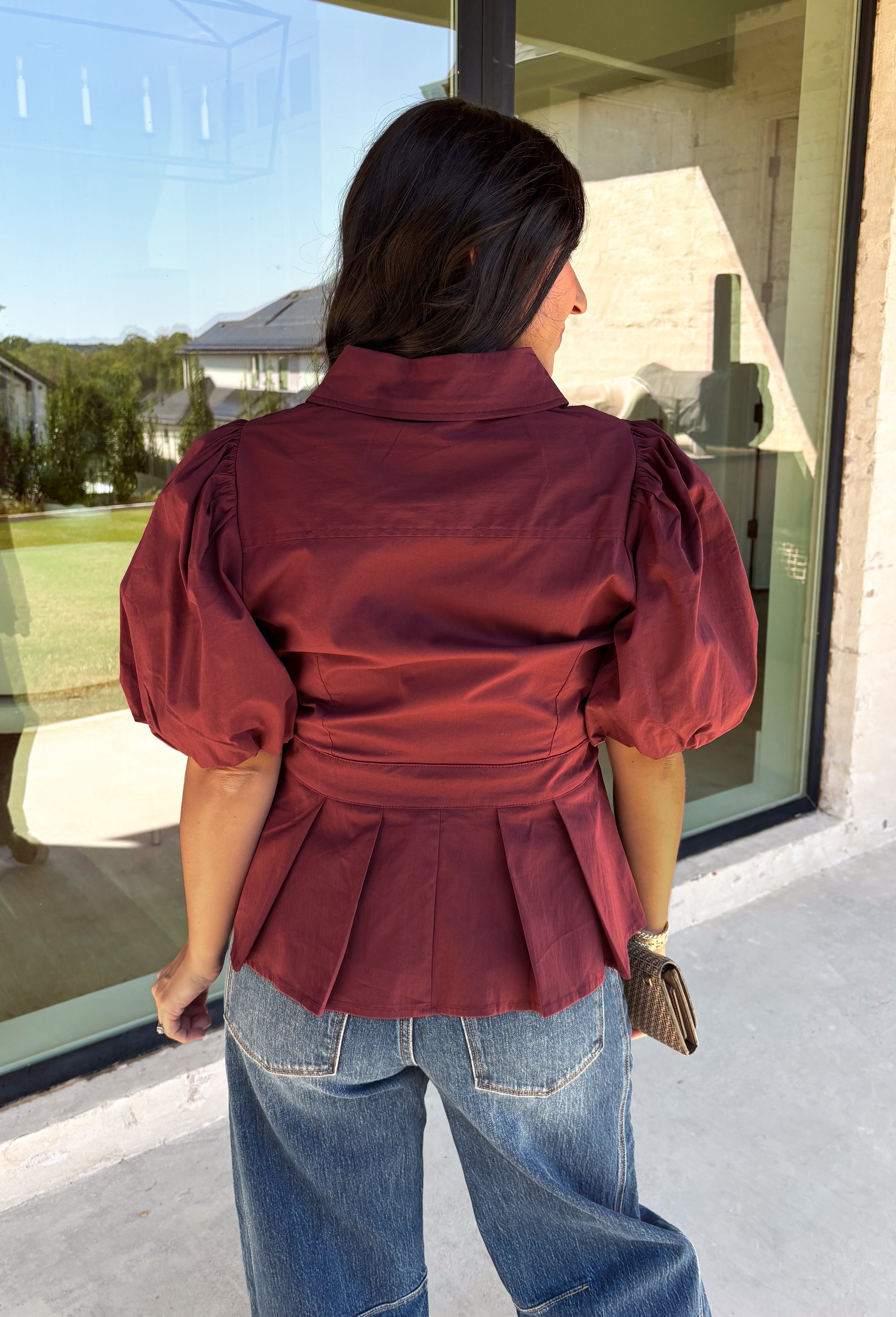 Rich burgundy and pretty shaping details make this top from Entro an easy pick for fall. The button-front design keeps the look classic, while a pleated waist and self-tie detail create a flattering shape that gives the silhouette a little something extra. Short puff sleeves add soft volume and balance out the fitted waist beautifully. Made from a cotton-blend fabric with a touch of stretch, it’s comfortable enough for all-day wear while still looking put together. 
