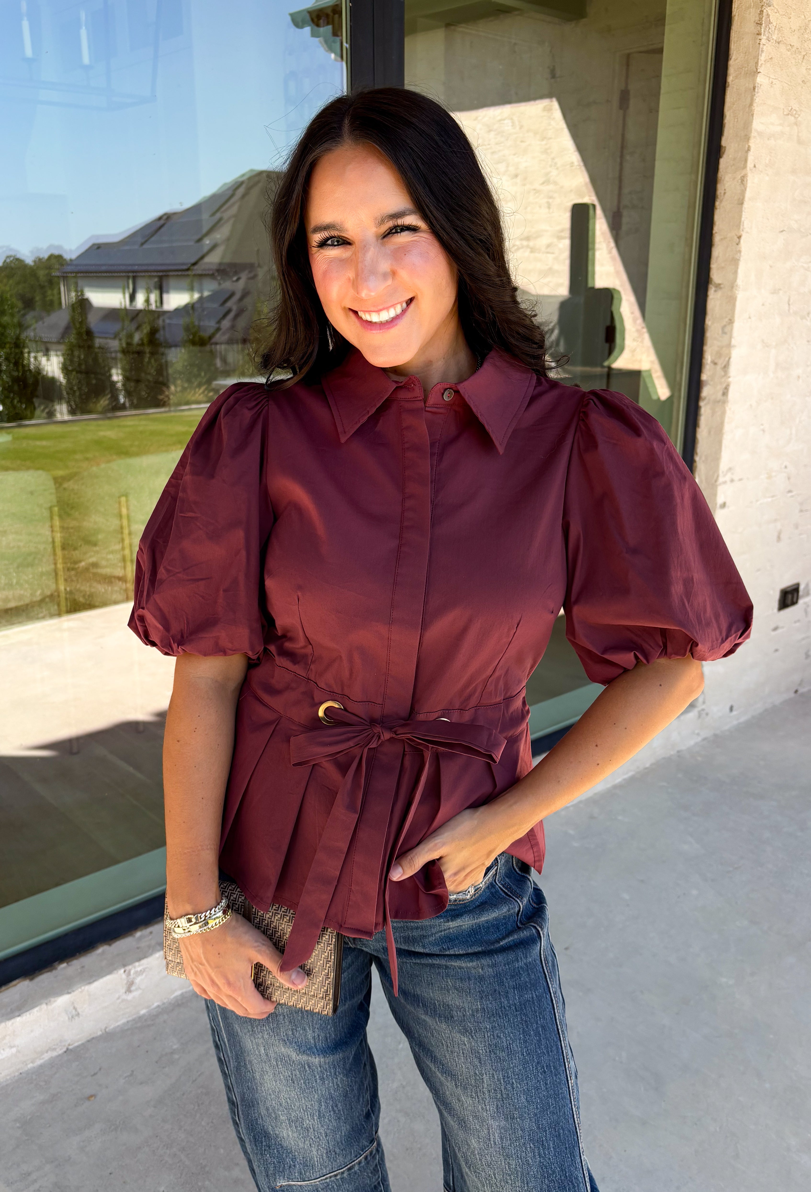 Rich burgundy and pretty shaping details make this top from Entro an easy pick for fall. The button-front design keeps the look classic, while a pleated waist and self-tie detail create a flattering shape that gives the silhouette a little something extra. Short puff sleeves add soft volume and balance out the fitted waist beautifully. Made from a cotton-blend fabric with a touch of stretch, it’s comfortable enough for all-day wear while still looking put together. 
