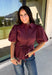 Rich burgundy and pretty shaping details make this top from Entro an easy pick for fall. The button-front design keeps the look classic, while a pleated waist and self-tie detail create a flattering shape that gives the silhouette a little something extra. Short puff sleeves add soft volume and balance out the fitted waist beautifully. Made from a cotton-blend fabric with a touch of stretch, it’s comfortable enough for all-day wear while still looking put together. 