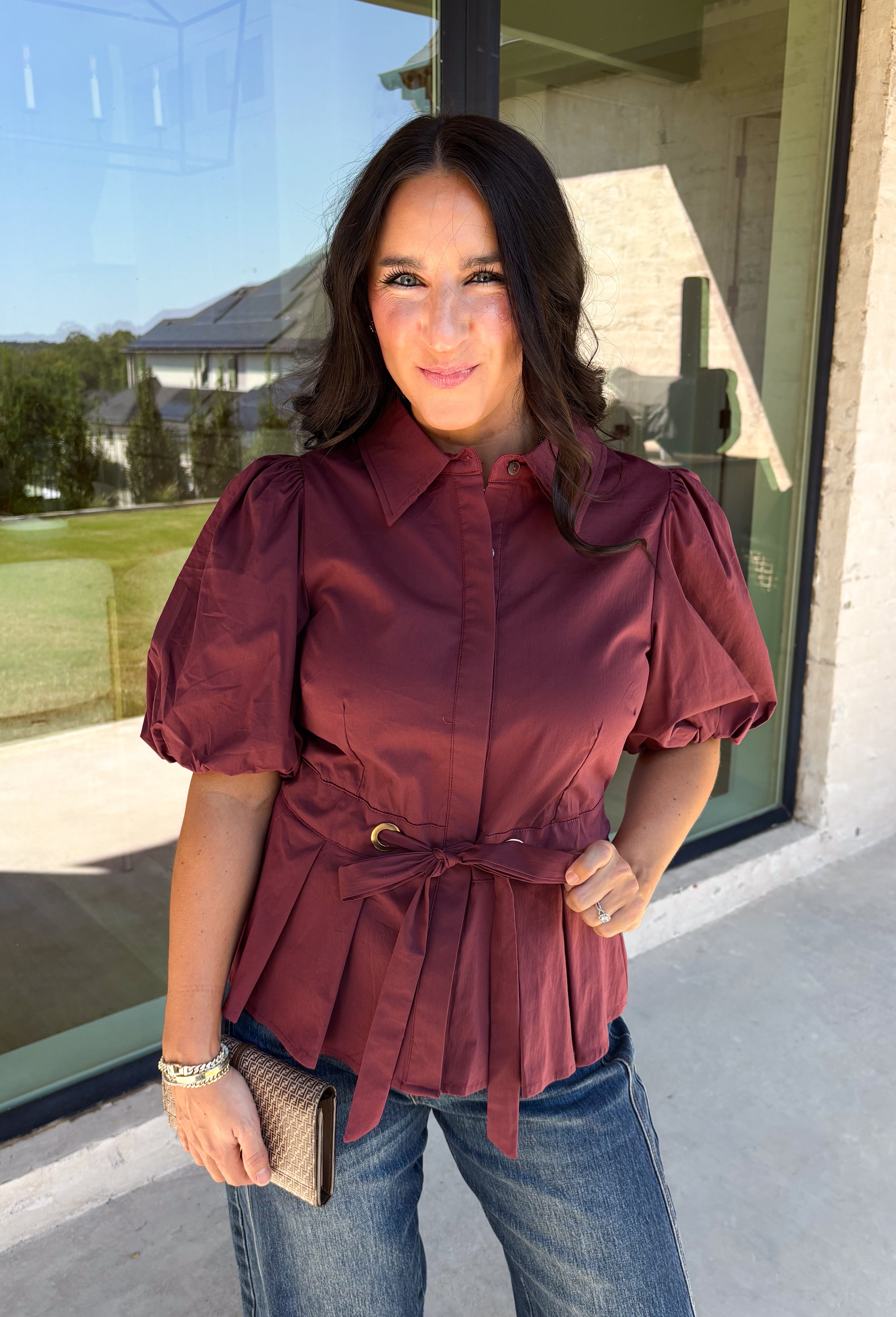 Rich burgundy and pretty shaping details make this top from Entro an easy pick for fall. The button-front design keeps the look classic, while a pleated waist and self-tie detail create a flattering shape that gives the silhouette a little something extra. Short puff sleeves add soft volume and balance out the fitted waist beautifully. Made from a cotton-blend fabric with a touch of stretch, it’s comfortable enough for all-day wear while still looking put together. 