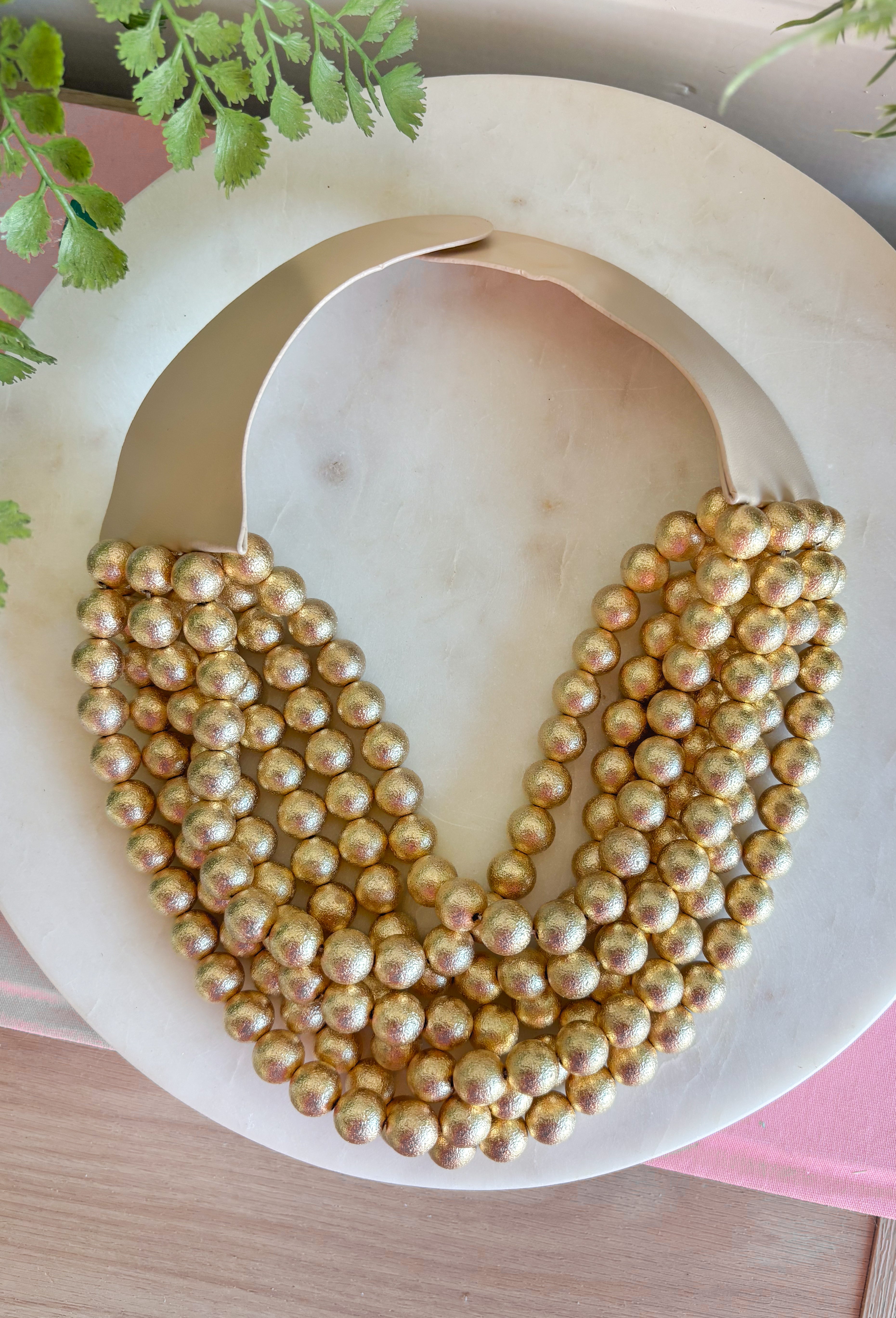 Add a pretty pop of gold to your look with this eye-catching layered beaded necklace. Featuring seven strands of gold beads, this chunky statement piece creates a full, dimensional look that makes even the simplest outfit feel a little more fun. The faux leather backing helps keep each layer beautifully arranged, while the magnetic closure makes it easy to put on and take off. It’s the perfect finishing touch for sweaters, dresses, blouses, and everyday basics.