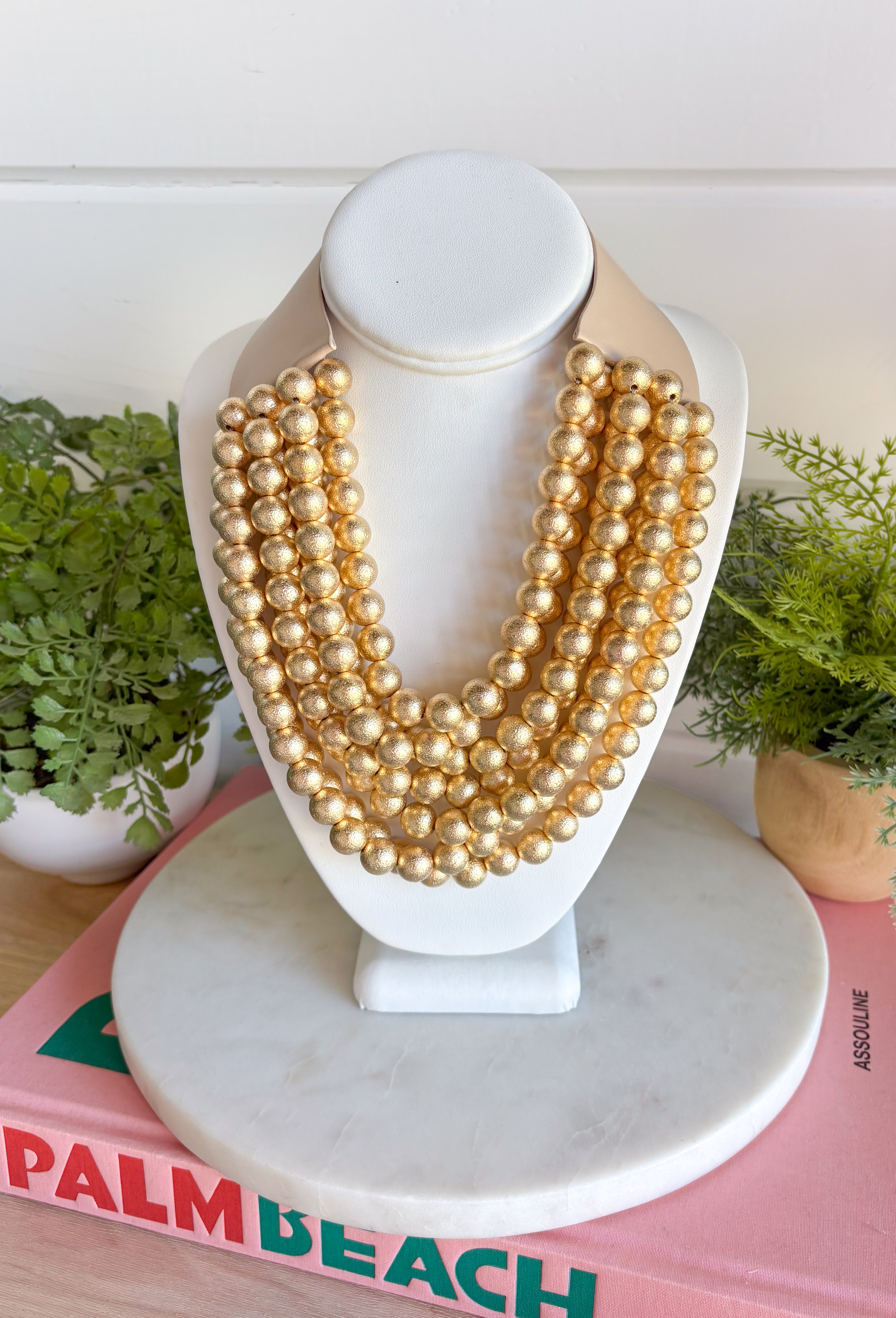 Add a pretty pop of gold to your look with this eye-catching layered beaded necklace. Featuring seven strands of gold beads, this chunky statement piece creates a full, dimensional look that makes even the simplest outfit feel a little more fun. The faux leather backing helps keep each layer beautifully arranged, while the magnetic closure makes it easy to put on and take off. It’s the perfect finishing touch for sweaters, dresses, blouses, and everyday basics.
