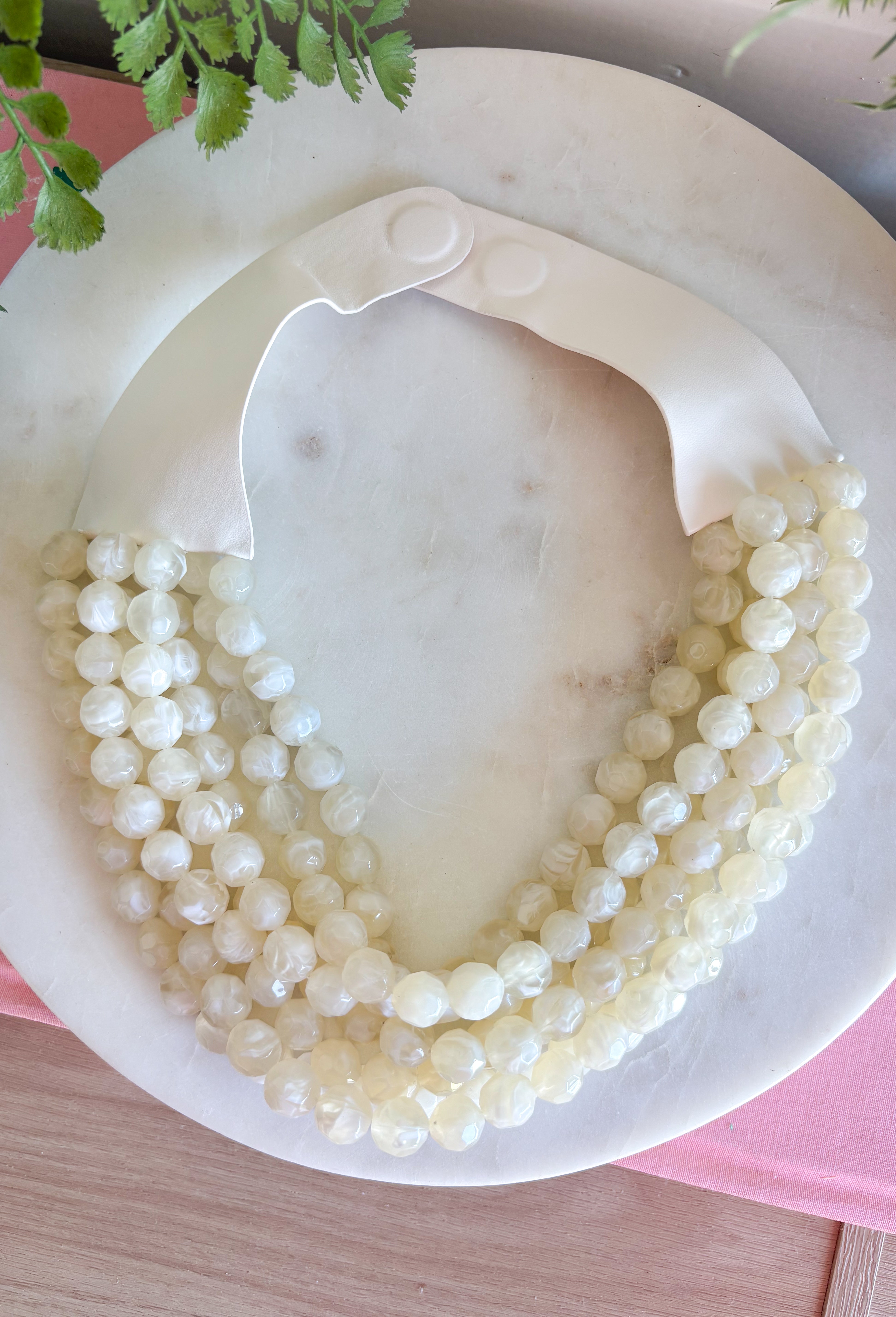 Add a soft, timeless touch to your look with this eye-catching ivory layered beaded necklace. Featuring seven strands of ivory beads, this chunky statement piece creates a full, dimensional look that makes even the simplest outfit feel a little more fun. The faux leather backing helps keep each layer beautifully arranged, while the magnetic closure makes it easy to put on and take off. It’s the perfect finishing touch for sweaters, dresses, blouses, and everyday basics.